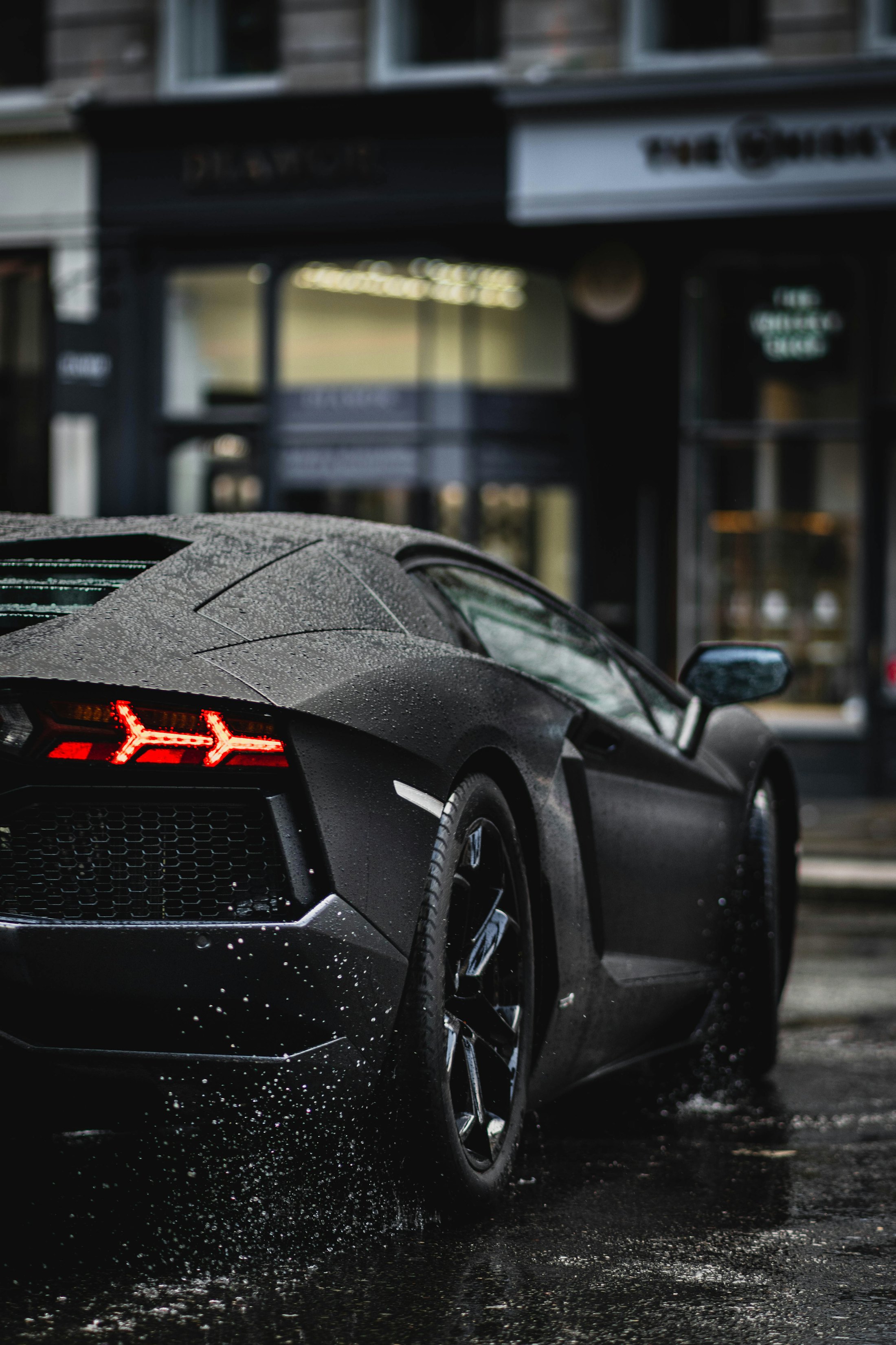A black sports car on a wet city street at night