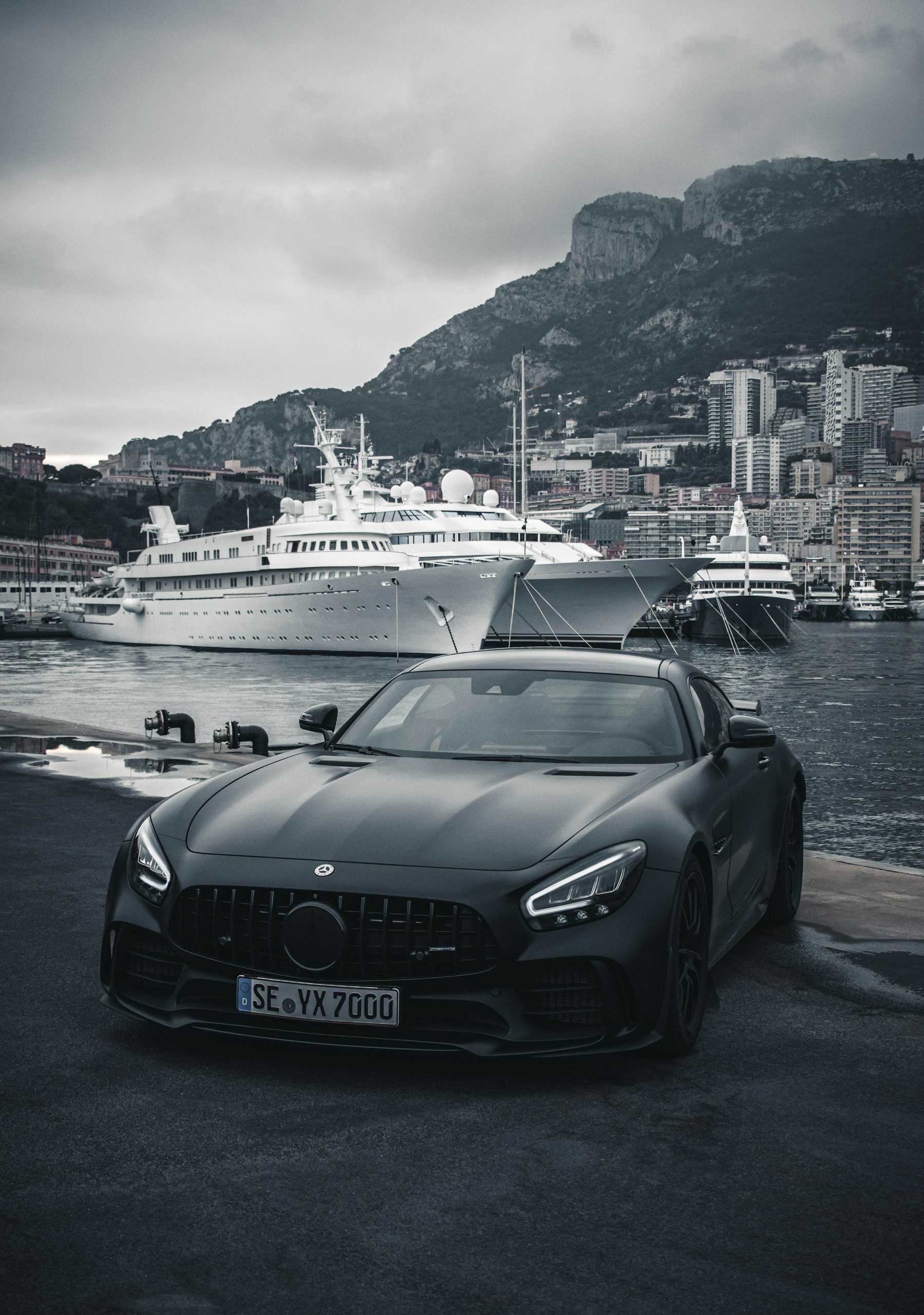 A matte black Mercedes-AMG coupe parked on a harbour quay